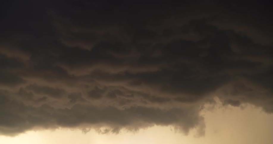 A close-up shot of a dark, ominous, and turbulent storm cloud filling the sky