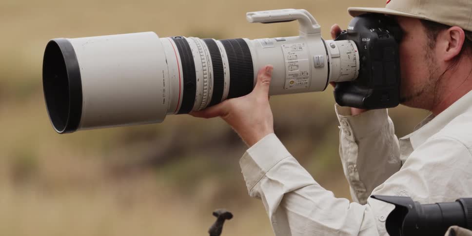 Man taking a photograph with a large lens