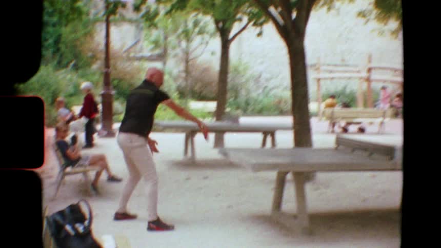Vintage Super 8mm footage of two men playing an energetic game of table tennis in a public park