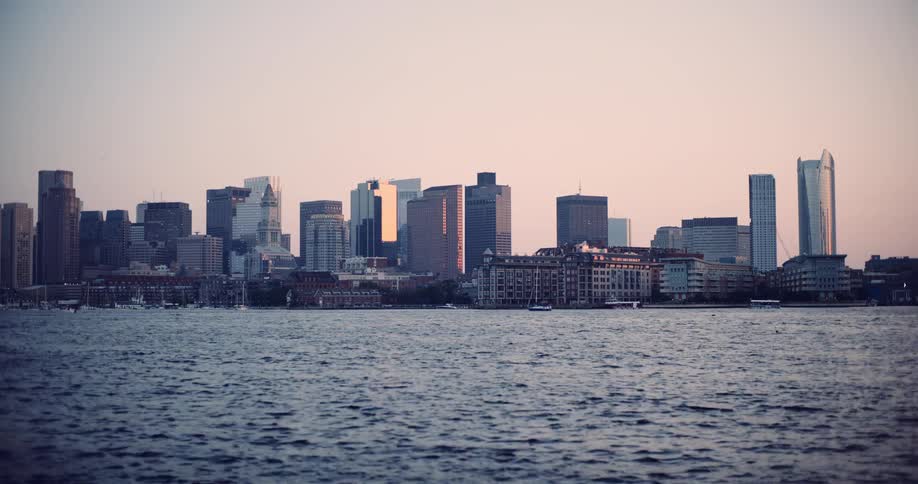 A beautiful static shot of the Boston, Massachusetts skyline at sunset with the tranquil harbor waters in the foreground