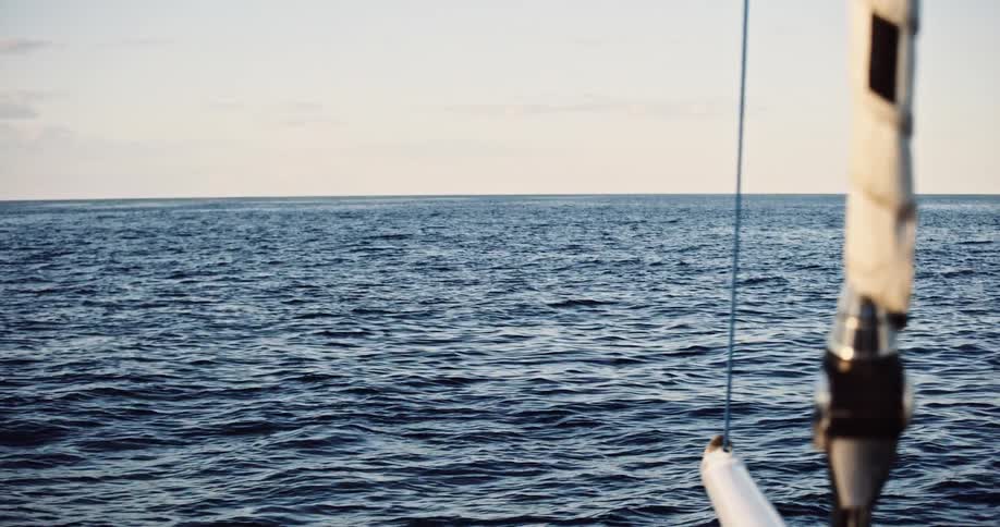 A tranquil scene of the vast ocean horizon as seen from a moving sailboat