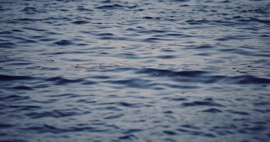 A serene, calming close-up of dark blue water gently rippling