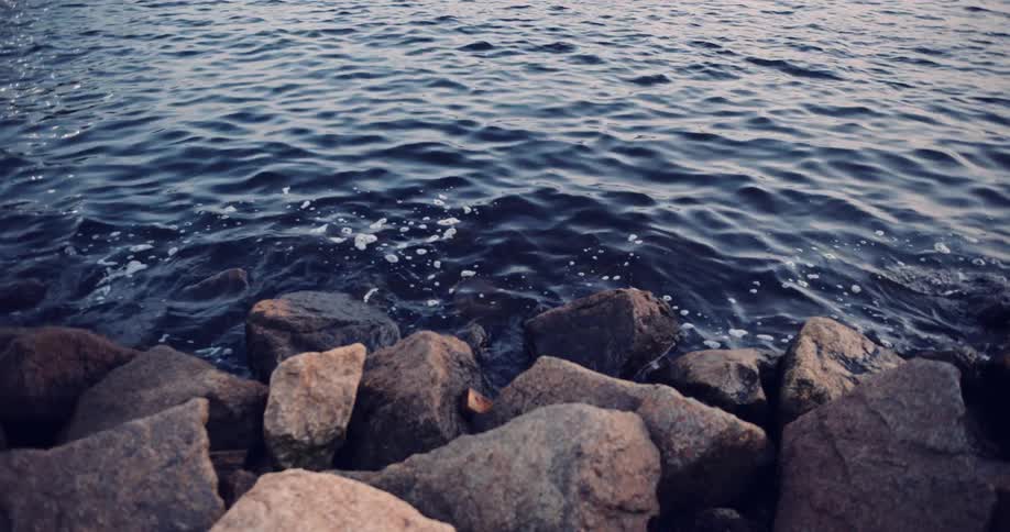 A tranquil close-up of dark blue water gently lapping against a rocky shore