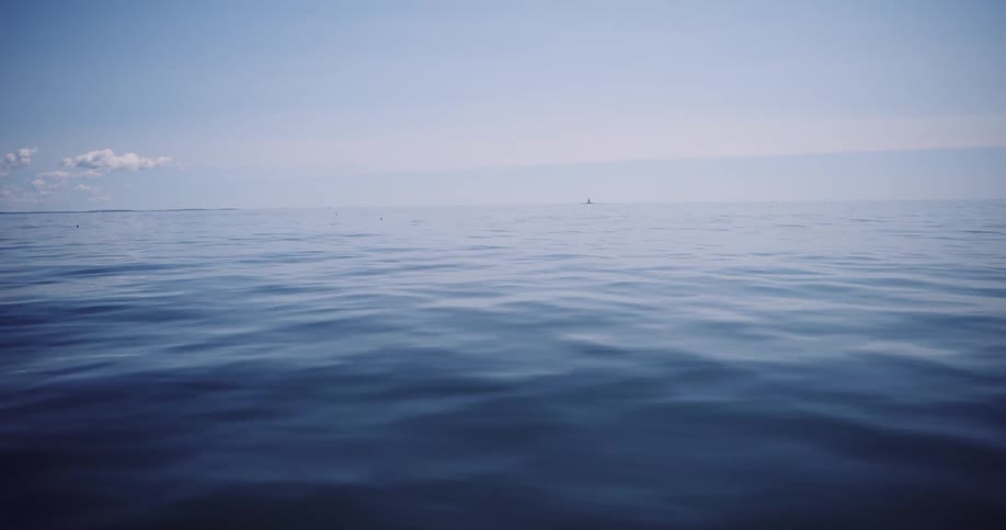 A tranquil shot of the calm, deep blue sea with gentle ripples stretching to the distant horizon