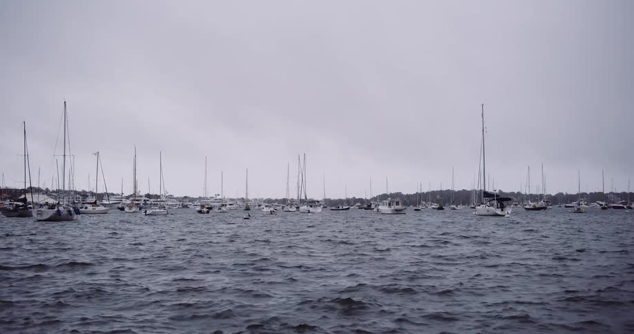 Sailboats moored in a choppy harbor on a gloomy, overcast day