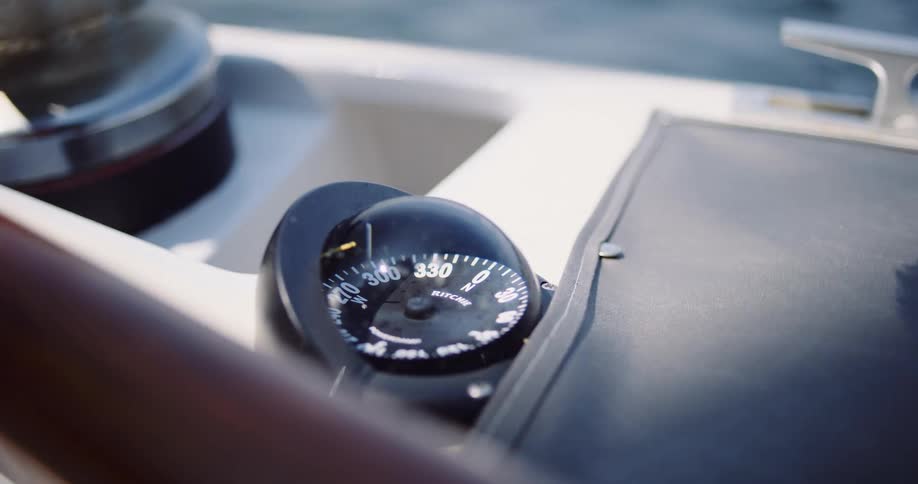 A close-up shot of a boat's compass rocking gently as the light fades from bright sun to shadow