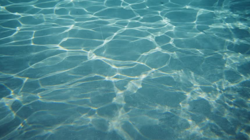 Peaceful underwater view of sunlight creating shimmering caustic patterns on the sandy seabed