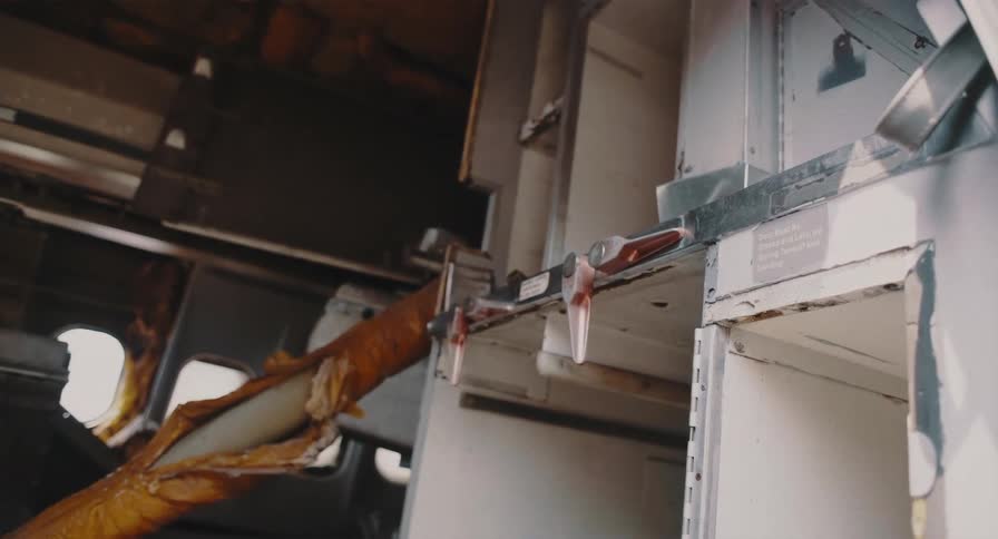 A close-up view of the destroyed interior and overhead compartments inside a wrecked airplane