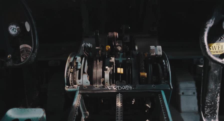 A steady shot of the decaying control levers inside the dark cockpit of a wrecked airplane