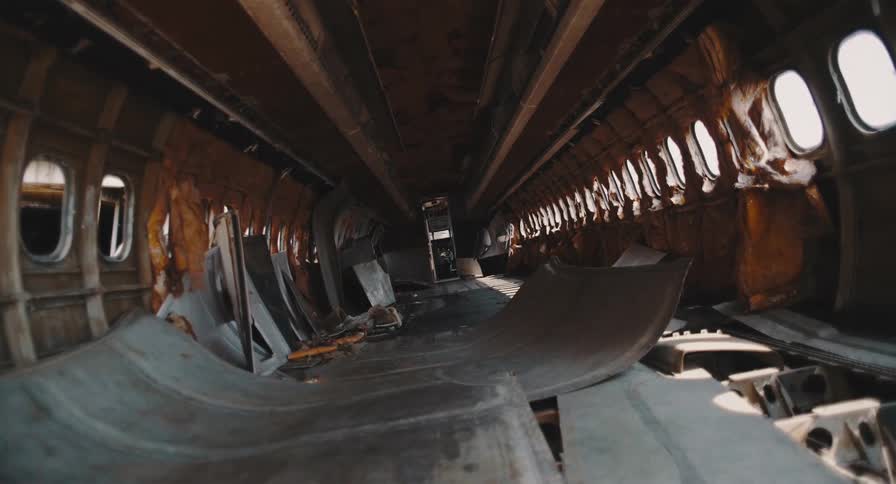 A static, wide-angle view of the desolate and destroyed interior of an abandoned airplane wreckage