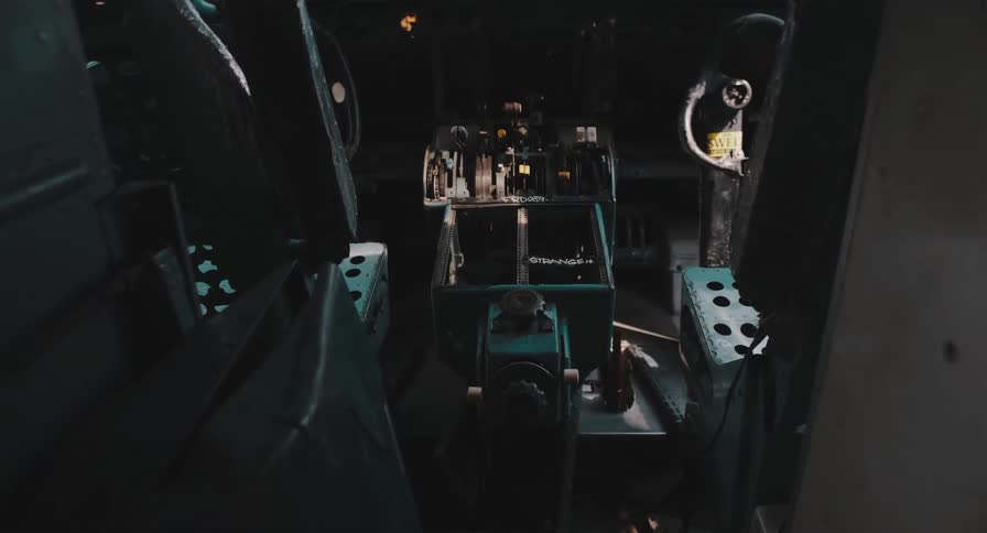 Shadows dance across the controls in the dark, abandoned cockpit of a derelict aircraft