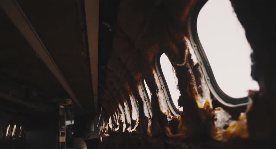 Sunlight streams through the windows of a derelict airplane's empty and stripped-down interior