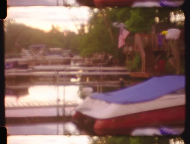 Dreamy vintage film captures a hazy, out-of-focus view of a quiet marina with docked boats at sunset
