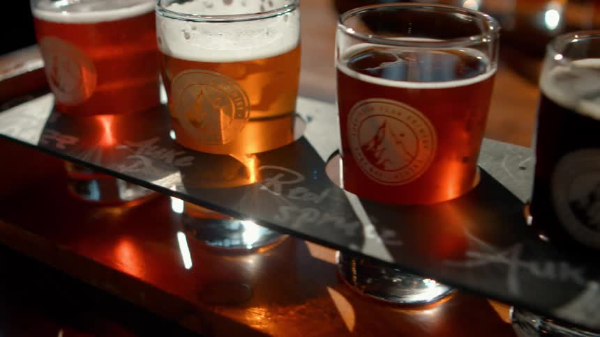 Close-up tracking shot of a craft beer flight with various ales and lagers ready for tasting at a local brewery