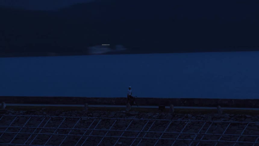 A cyclist pauses for a rest while walking along a reservoir at dusk in a stunning long exposure shot