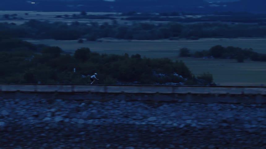 Aerial side-view of a cyclist training on a rural path during the blue hour at twilight