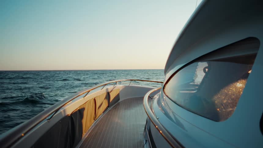 A serene view from the deck of a modern yacht sailing on the open ocean during a beautiful golden hour