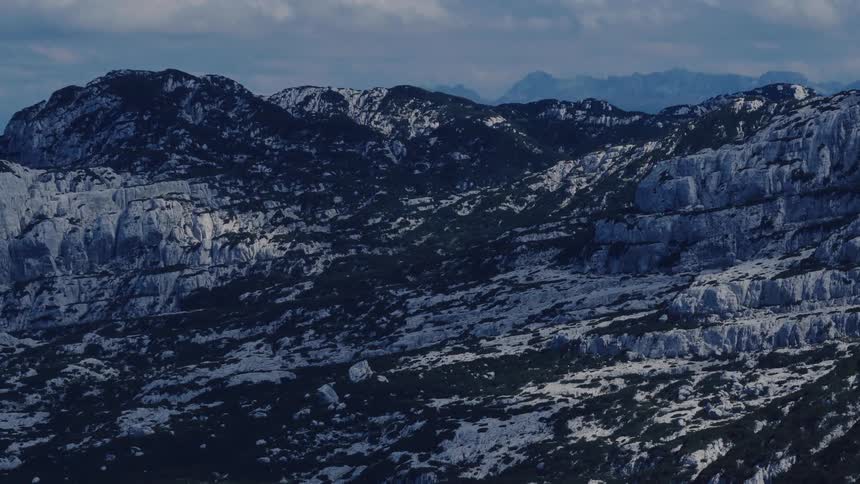 A time-lapse of shadows and clouds moving across a vast, rugged, and rocky mountain range