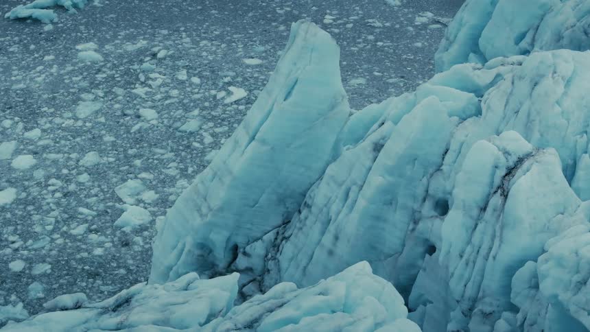 Jagged blue ice formations of a massive glacier rise above the frigid, ice-filled water