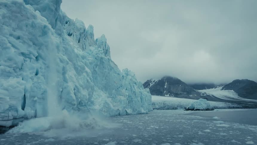 Dramatic footage of a massive glacier calving, sending a cascade of ice and snow into the icy arctic waters