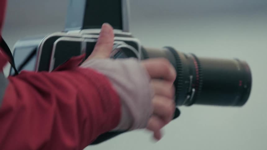 Close-up of a photographer in winter gear capturing images with a film camera from a moving boat