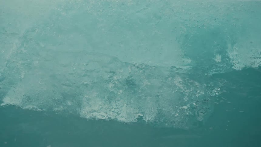 A detailed close-up shot shows a massive blue glacier slowly melting into the turquoise arctic water