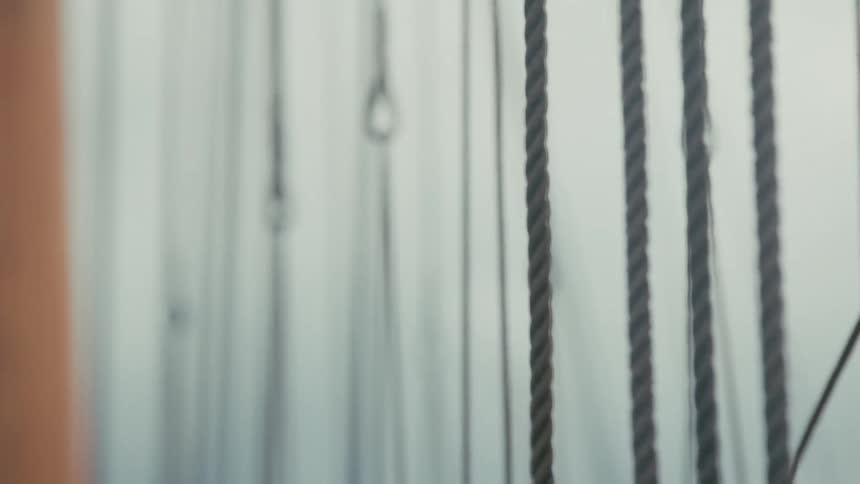 A tranquil, soft-focus close-up of the intricate ropes and rigging on a sailboat