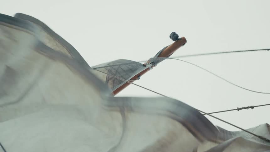 Close up on a weathered sail flapping and billowing wildly in the strong wind on a boat
