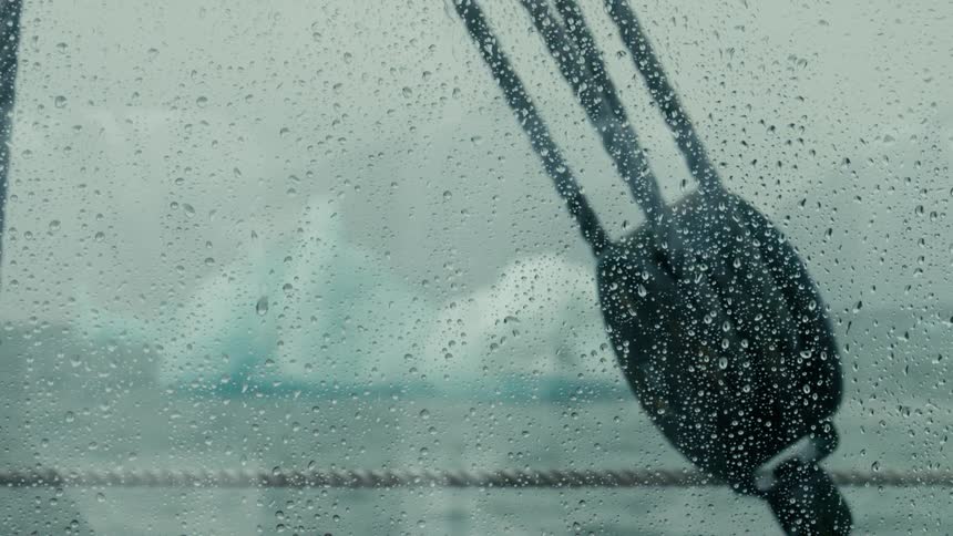 Close up of rain on a window looking out at an iceberg and arctic waters from a boat