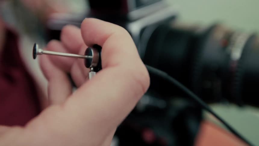 A photographer's hand uses a mechanical shutter release cable to trigger a vintage medium format camera