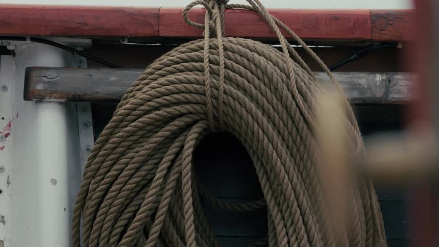 Thick nautical rope coiled and stored on the side of a moving vessel