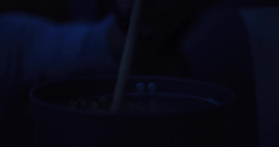 A person stirs a steaming meal in a pot with a spoon during a dark night while camping