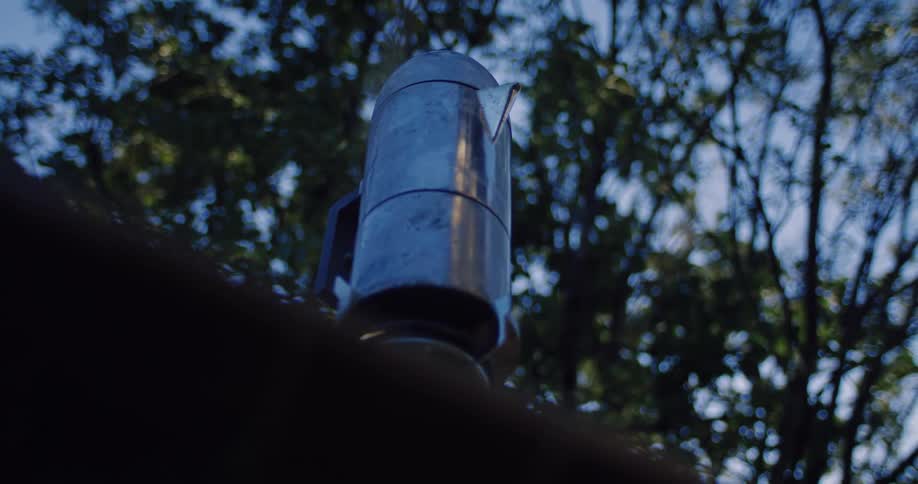 A rustic metal coffee percolator steams while brewing a fresh pot at an outdoor campsite