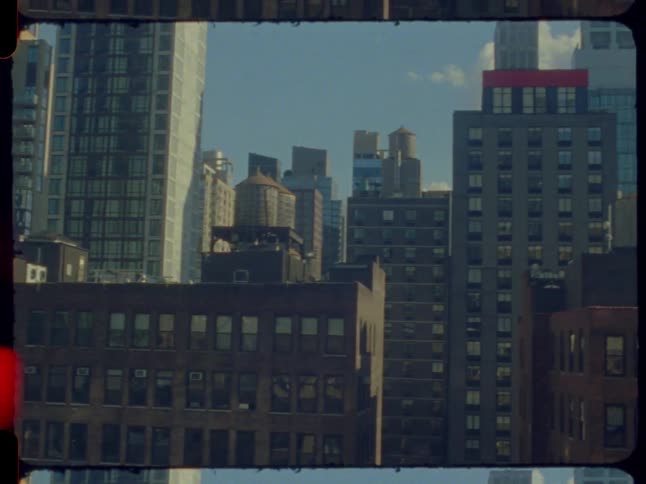 A vintage film shot pans across a sunny New York City skyline featuring skyscrapers and iconic water towers