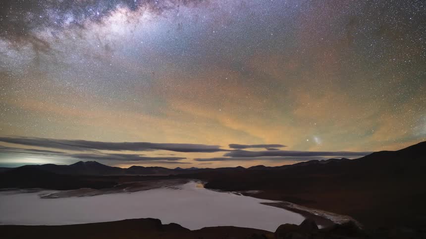 An epic day-to-night-to-day timelapse over a vast mountain valley and salt flat shows the Milky Way galaxy and a beautiful sunrise