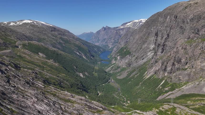 Epic aerial footage slowly pushes through the majestic Trollstigen mountain pass in Norway on a beautiful sunny day