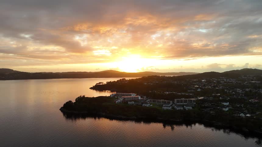 A stunning static aerial view captures the golden sunset over a tranquil coastal town nestled by the water