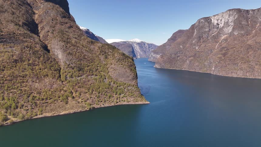 Static aerial shot of a majestic fjord in Norway with towering mountains and snow-capped peaks in the distance