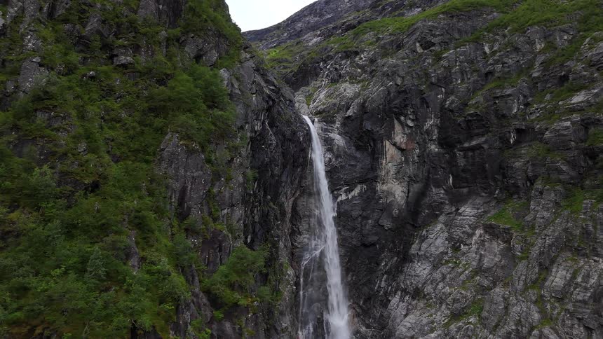 A digital composite shows a majestic waterfall materializing and cascading down a steep, rocky cliffside covered in green foliage