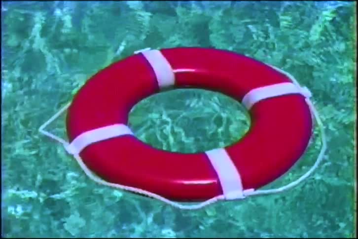 A vintage-style shot of a red life preserver floating on the clear, calm surface of turquoise water