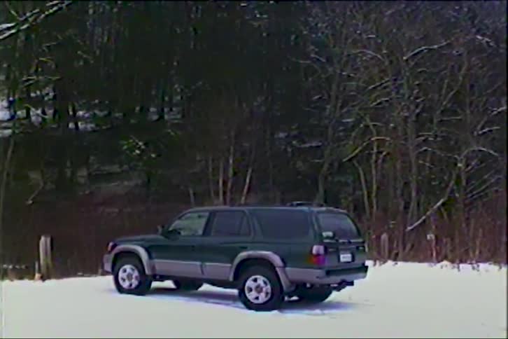 Vintage VHS home video captures a green SUV parked in the quiet, snowy woods