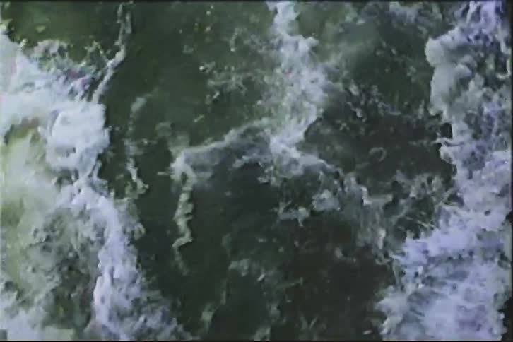 Vintage footage shows a powerful, fast-flowing river with churning white water rapids from an overhead perspective