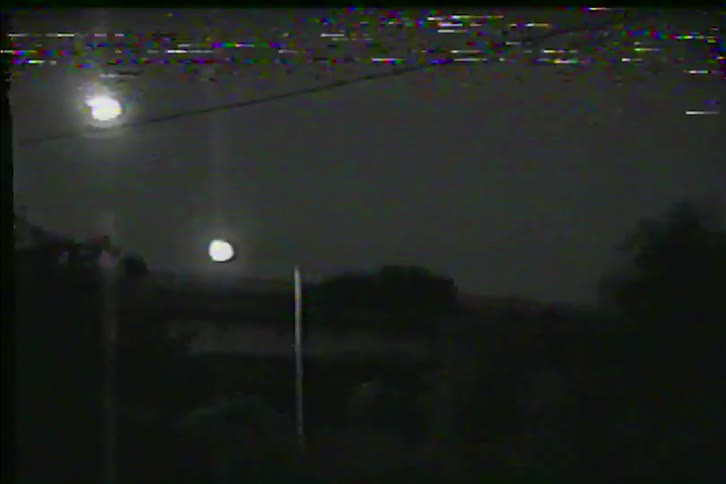 Vintage VHS footage shows a dramatic lightning storm illuminating the night sky with heavy visual distortion