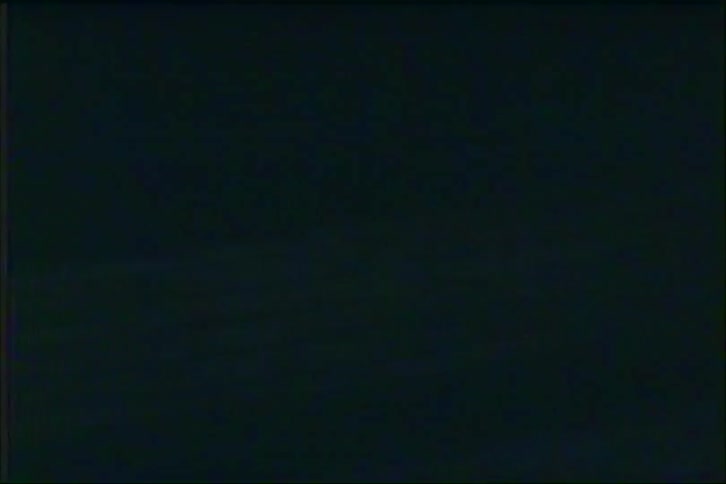 Vintage analog footage shows abstract, blurry streaks of colorful lights moving rapidly at night