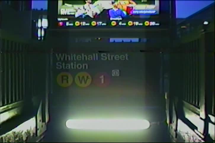 A gritty, vintage VHS-style shot descends the stairs into the Whitehall Street subway station at night