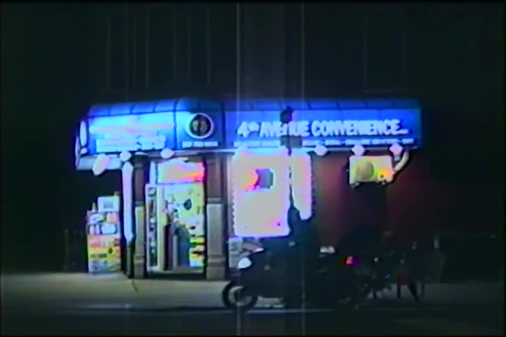 A vintage VHS recording shows a scooter driving past an illuminated urban convenience store late at night