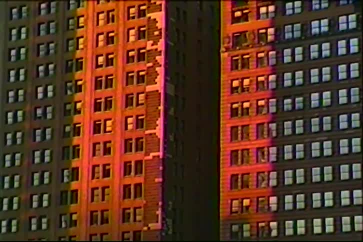 Warm sunset light illuminates the brick facades of two classic city skyscrapers
