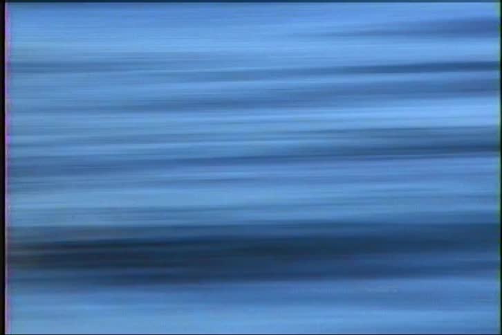 A fast-moving, blurry shot of the water's surface creates an abstract streaky blue background
