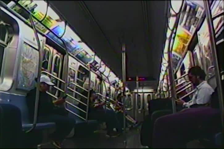 Retro VHS-style footage captures the quiet interior of a subway car as passengers commute at night