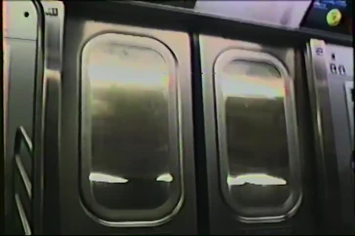 Vintage VHS footage shows the reflective interior doors of a moving subway train as lights and scenery pass by